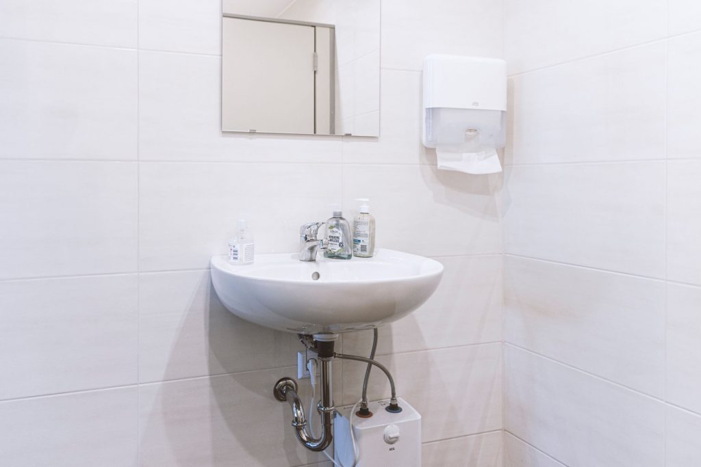 Waschbecken mit Spiegel und Warmwasserboiler auf der Damen-Toilette