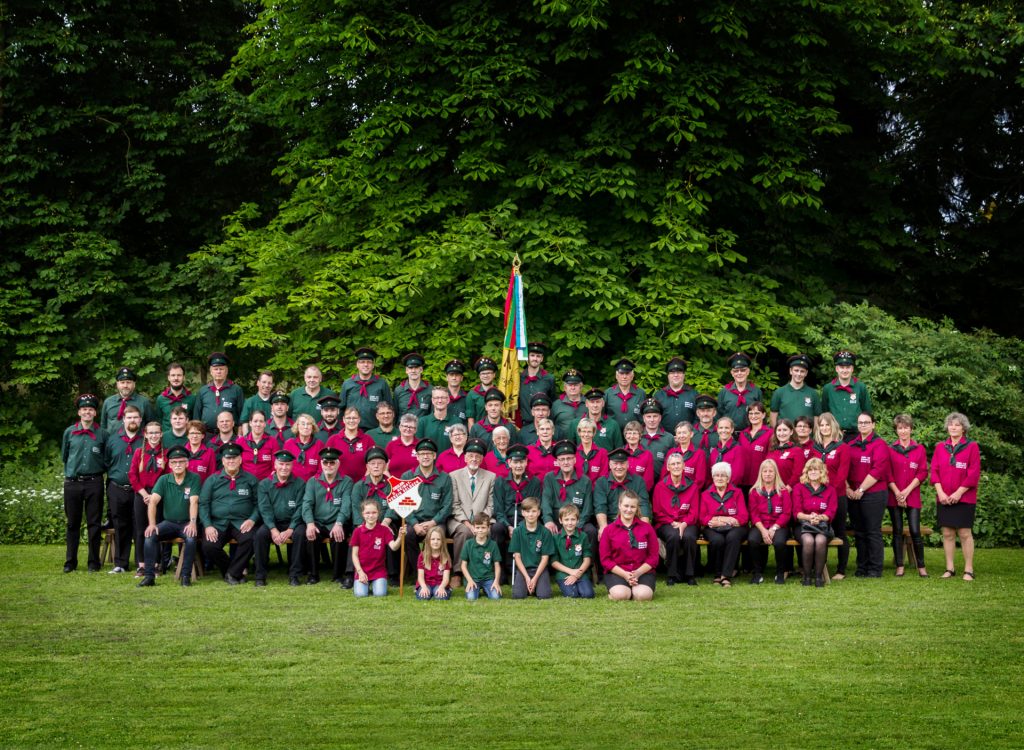 Vereinsfoto aus dem 2019 mit circa 70 aktiven Mitgliedern in Vereinsuniform und Fahnen.