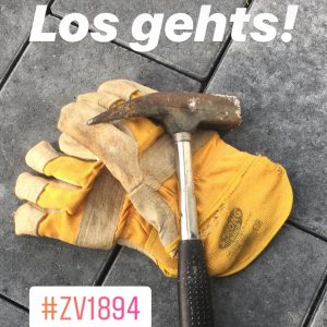 Arbeitshandschuhe und Hammer auf einem Steinboden
